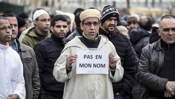 Ein französischer Muslim hält am 9. Januar in Saint-Etiennevor einer Moschee ein Schild mit der Aufschrift „Nicht in meinem Namen“, um gegen den Anschlag von Paris zu protestieren. Muslime die an Allah den Barmherzigen glauben und Barmherzigkeit in ihren Herzen haben wollen. Früher nannte man Muslime Mohammedaner. Sind radikale Islamisten mehr Mohammedaner? Mohammed hat zu seiner Zeit schon einen Islamischen Staat angefangen aufzubauen. 